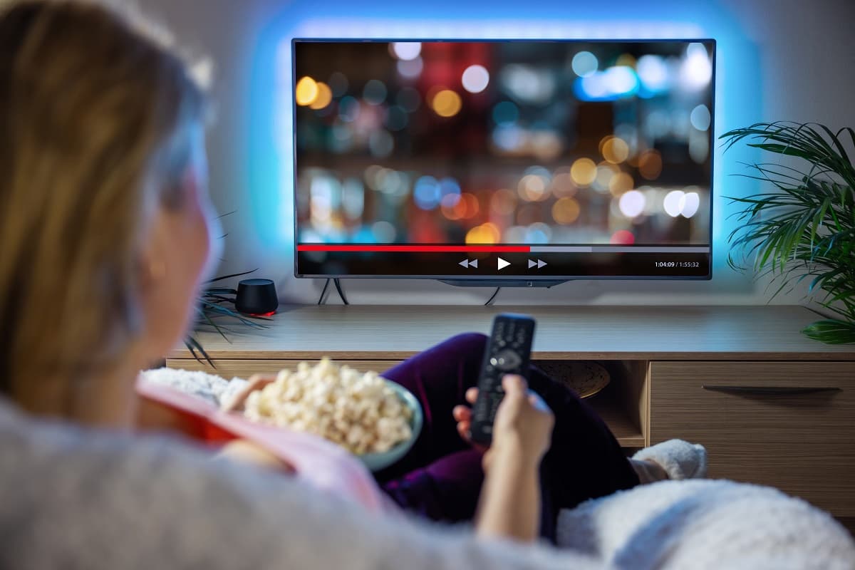 Femme dans canapé avec popcorn, devant la SVoD de sa télé à 1€ l'abonnement grâce à sa Livebox Max